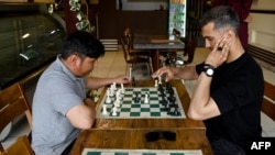 Men play chess at the Cupcake Coffee Shop cafe in Kabul On May 11.