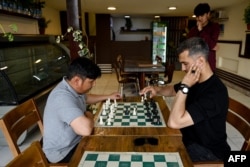 مردان درست قبل از اینکه طالبان این ورزش را در 11 مه 2025 به حالت تعلیق درآورد ، در کافه کافی شاپ کیک در کابل بازی می کنند.
