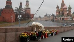 A woman adjusts flowers at the site of the assassination of Kremlin critic Boris Nemtsov in central Moscow, March 20, 2017