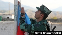 Азербайджанский военный поднимает государственный флаг в селе в Нагорном Карабахе