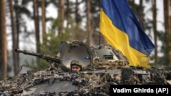 Ukrainian servicemen ride on an armored transporter as they pass through a Russian position overrun by Ukrainian forces outside Kyiv on March 31. 