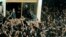 Some of the thousands of people who on daily basis jammed a schoolyard in Tehran to see the Ayatollah Rouhollah Khomeini immediately after his return to Iran, who blesses the crowd, is pictured, Feb. 4, 1979. 
