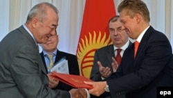 Kyrgyzgaz chairman Turgunbek Kulmurzaev (left) and Gazprom CEO Aleksei Miller (R) exchange documents during a signing ceremony in Bishkek sealing a deal for the Russian energy giant to buy the Kyrgyz corporation for a symbolic sum in April. 