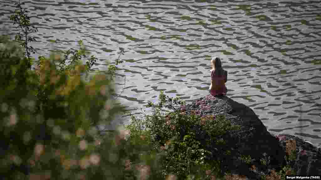 Жінка присіла на березі озера