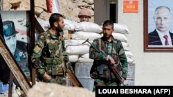 Siriýanyň prezidenti Başar al-Assadyň we Russiýanyň prezidenti Wladimir Putiniň portretleriniň arasynda duran siriýaly esgerler.