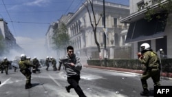 A demonstrator runs away from riot police during a protest in Athens on May 11, 2011 