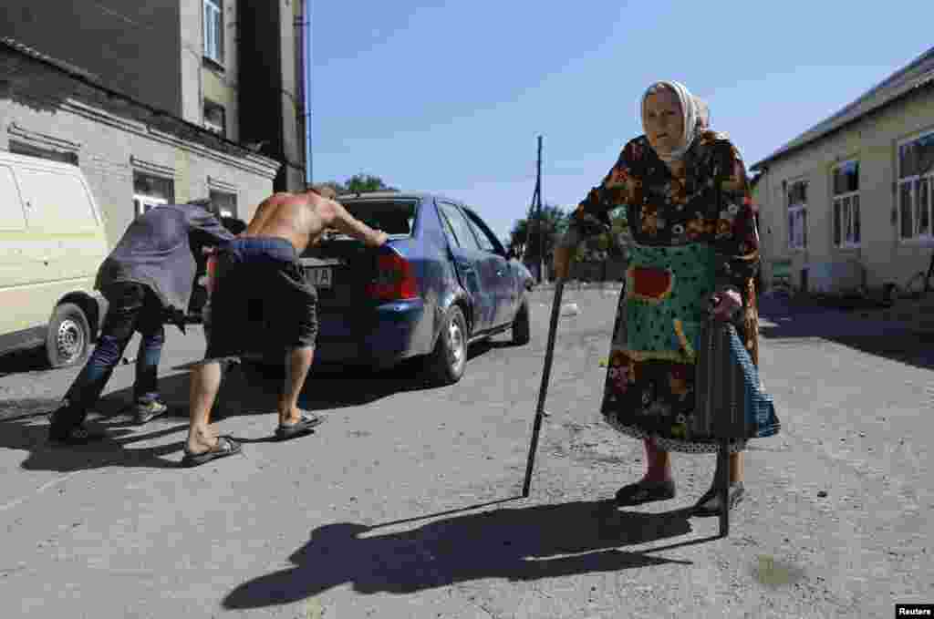 People push a broken-down car past a woman in the eastern Ukrainian town of Ilovaysk. (Reuters/Maxim Shemetov)