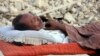 A survivor of the Balochistan earthquake sleeps near the rubble of his mud house. 