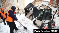 Utility workers shovel snow on Suvorovsky Prospekt Street in St. Petersburg on January 10.