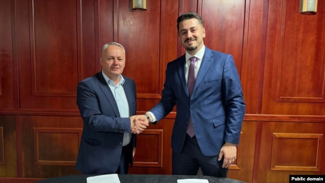 Agron Kuçi i AAK-së (majtas) duke shtrënguar duart me Jetmir Tofajn e LVV-së pas arritjes së koalicionit në Junik. Më 9 nëntor, Kuçi përballet me kandidatin e LDK-së, Ruzhdi Shehun.