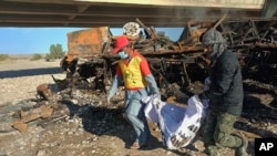 Rescue workers collect human remains from the burned wreckage of the bus accident on January 29.