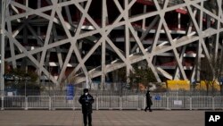 Stražari ispred nacionalnog stadiona u Pekingu, 31. januar 2022.