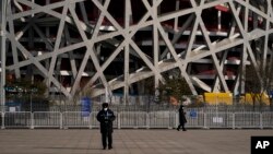 Një roje qëndron pranë Stadiumit Kombëtar të Pekinit para Lojërave Olimpike Dimërore. Janar, 2022. 
