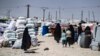 Families carry their belongings at the Kurdish-run Al-Khol camp, which holds relatives of suspected Islamic State fighters in Syria.