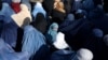 A girl waits among a crowd of Afghan women waiting to receive bread from a Kabul bakery.