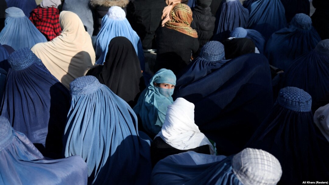A girl waits among a crowd of Afghan women waiting to receive bread from a Kabul bakery.