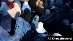 A girl waits among a crowd of Afghan women waiting to receive bread from a Kabul bakery.
