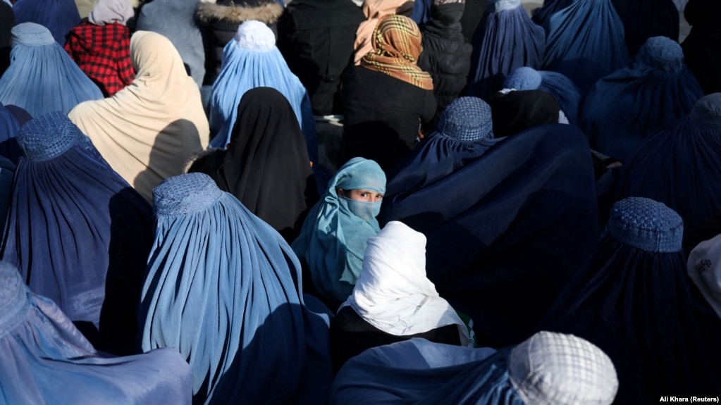 A girl waits with Afghan women to receive bread from a bakery in Kabul.