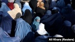 A girl waits with Afghan women to receive bread from a bakery in Kabul.