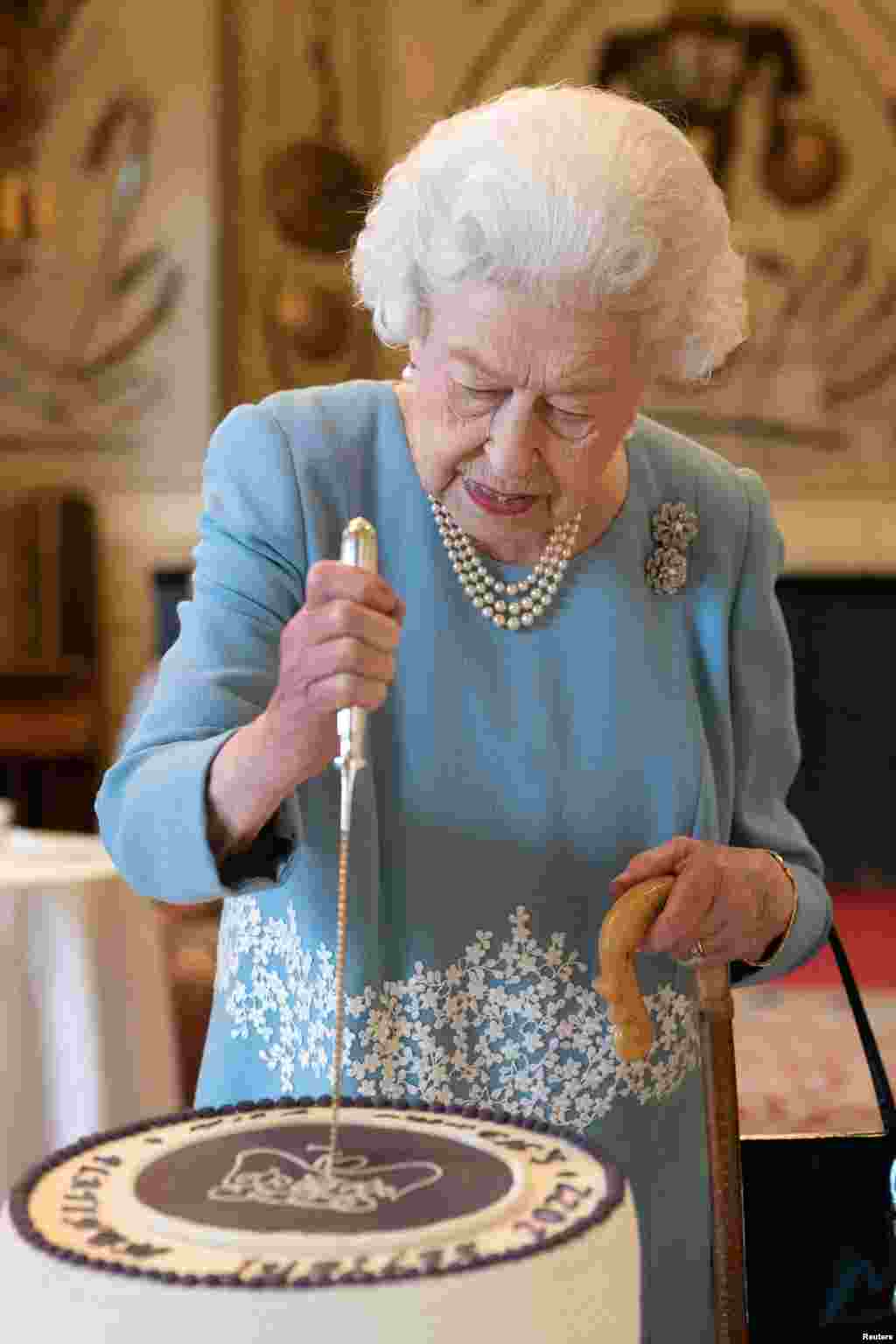 Regina Elisabeta taie tortul aniversar dedicat Jubileului de Platină la recepția din 5 februarie de la Sandringham House, reședința Reginei din Norfolk, Marea Britanie.