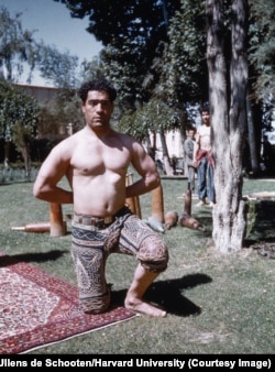 A practitioner of zoorkhaneh -- a traditional Persian athletics and martial arts discipline -- photographed in Malayer, western Iran. The wooden instruments in the background are a kind of ancient exercise equipment known as meels.