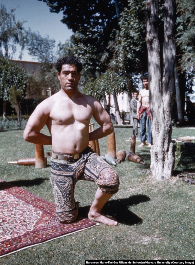 A practitioner of zoorkhaneh -- a traditional Persian athletics and martial arts discipline -- photographed in Malayer, western Iran. The wooden instruments in the background are a kind of ancient exercise equipment known as meels.