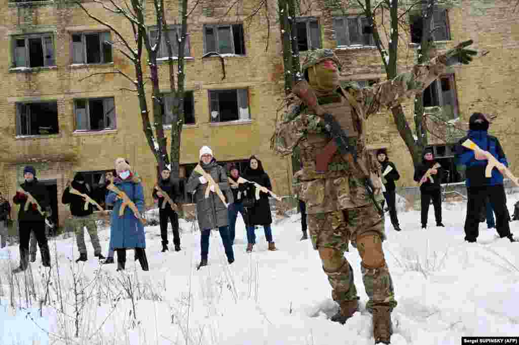 A military instructor teaches civilians holding wooden replicas of Kalashnikov rifles during a training session at an abandoned factory in the Ukrainian capital, Kyiv, on January 30, amid continuing fears of a Russian invasion.