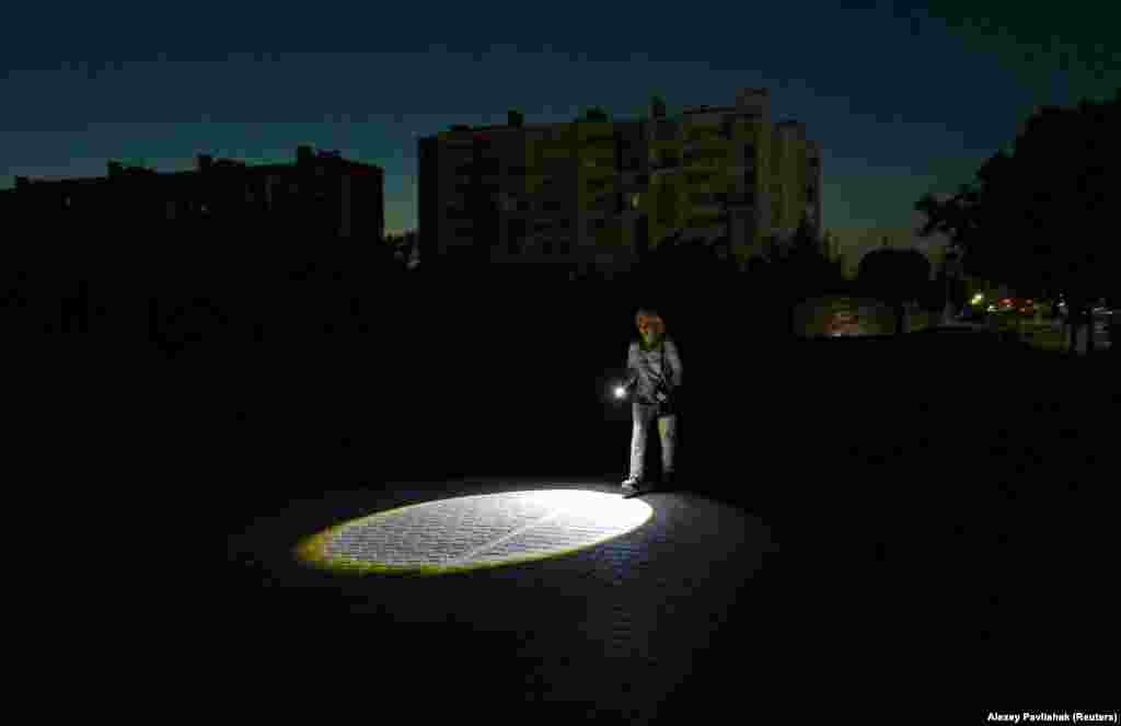 A woman walks with a flashlight during a blackout in the western Crimean city of Yevpatoria on July 5.A series of Ukrainian drone strikes targeting Crimea's electricity grid over the past week has caused sweeping blackouts through much of the Russian-occupied peninsula.