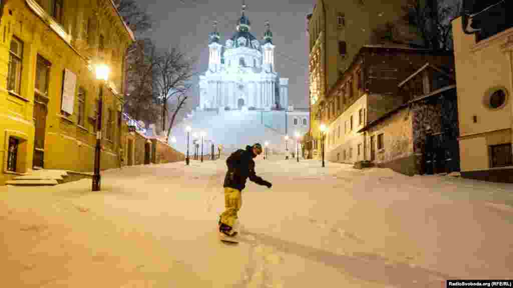 Сноубордист едет по улице после выпадения 30 сантиметров снега в Киеве, 9 февраля​