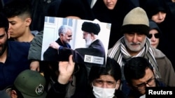 Un manifestant ține o poză a liderului ayatollah Ali Khamenei cu Qassem Soleimani, în timpul protestului împotriva asasinării ultimului, Teheran, 3 ianuarie 2020