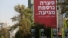 People walk past a billboard bearing a message in Farsi and in Hebrew that reads "another storm is coming', in Tehran on October 27, 2024.