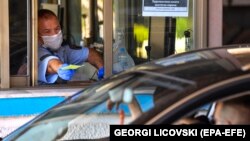 NORTH MACEDONIA --Police officer takes documents from a motorist at the 'Bogorodica' border crossing between North Macedonia and Greece, near the southern city of Gevgelija, North Macedonia, 01 July.