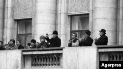 Pe 21 decembrie, din balconul CC, soții Ceușescu văd că tensiunile nu pot fi potolite cu promisiuni. „Cutremur?” a întrebat Elena Ceaușescu când oamenii adunați la un miting menit să calmeze spiritele au început să devieze de la scenariul muncitorilor recunoscători partidului.