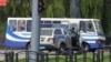 Правоохоронці лежать на землі за автомобілем біля пасажирського автобуса, захопленого зловмисником у Луцьку, 21 липня 2020 року