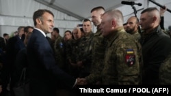 Francuski predsjednik Emmanuel Macron (lijevo)rukuje se s ukrajinskim vojnicima tokom posjete vojnom kampu gdje Francuska obučava ukrajinske trupe za borbu protiv ruske invazije, u istočnoj Francuskoj 9. oktobra 2024. 