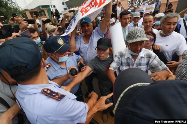 Полицейские пытаются отобрать плакаты у участников митинга. Алматы, 6 июля 2021 года