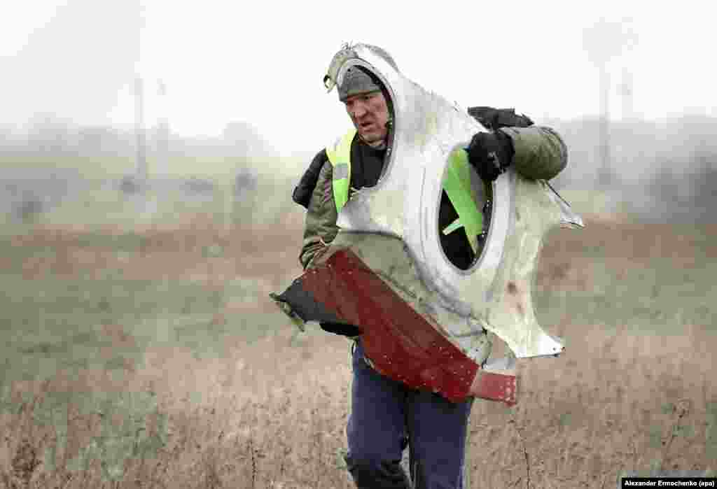 A November 2014 photo of a man carrying a piece of the aircraft from the crash site inside Ukrainian territory held by Russia-backed separatists. Dutch inspectors commissioned the emergency services of the separatist group that calls itself the Donetsk People&#39;s Republic to collect the wreckage after saying the area was too dangerous for their staff.&nbsp;