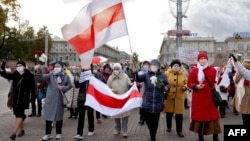 Belarusian pensioners carrying banned white-red-white flags and flowers parade through the streets of Minsk during a rally to demand the resignation of authoritarian leader Alyaksandr Lukashenka and a new fair election on October 19.