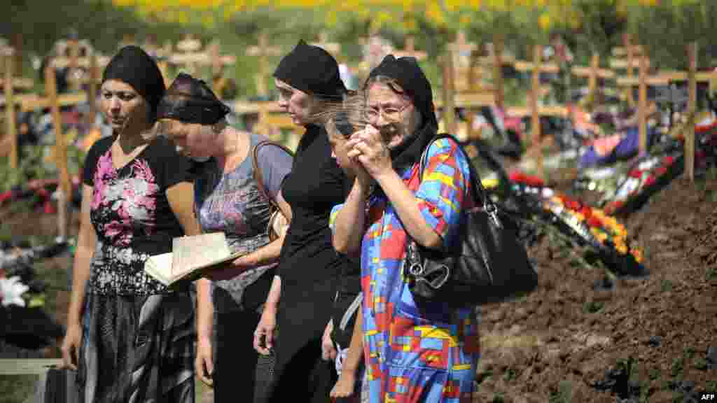 Women mourn at the grave of a flood victim at Krymsk&#39;s cemetery on July 9.