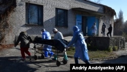 Egészségügyi dolgozók viszik egy Covidban meghalt beteg holttestét az ukrajnai Kramatorszk hullaházába 2021. október 30-án