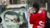 A woman uses her mobile phone near a damaged picture of Syrian President Bashar al-Assad as people celebrate, in Qamishli