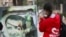 A woman uses her mobile phone near a damaged picture of Syrian President Bashar al-Assad as people celebrate, in Qamishli