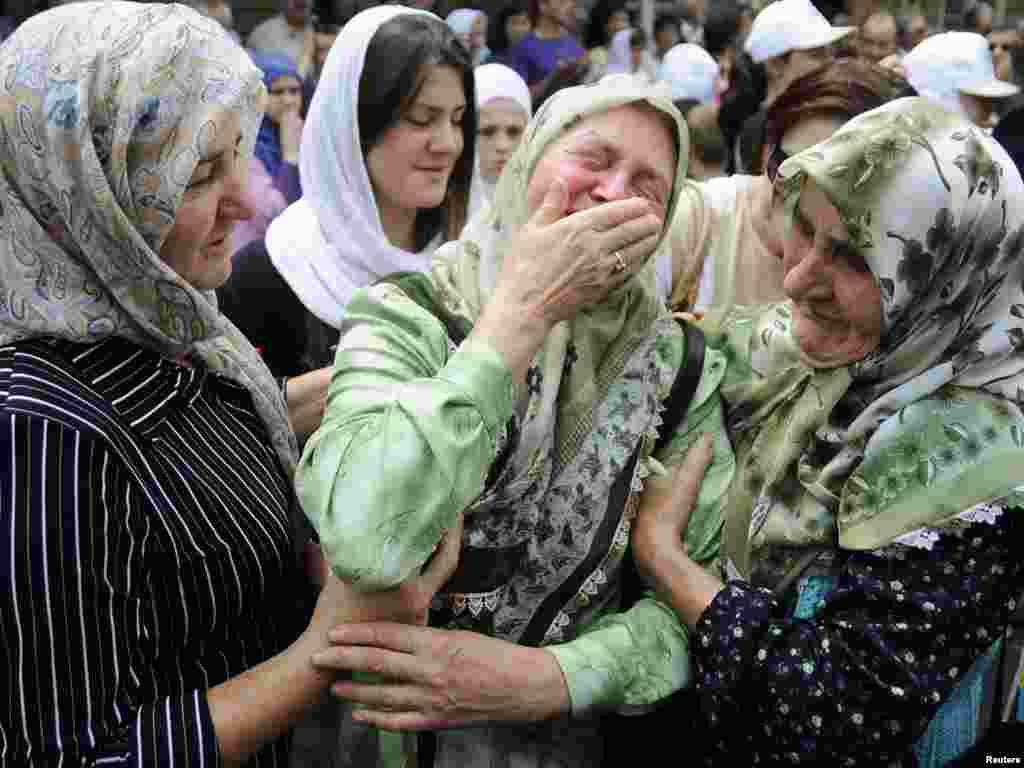 A Bosnian woman cries beside trucks loaded with the coffins of 775 newly identified victims of the 1995 Srebrenica massacre in Sarajevo in July 2010.