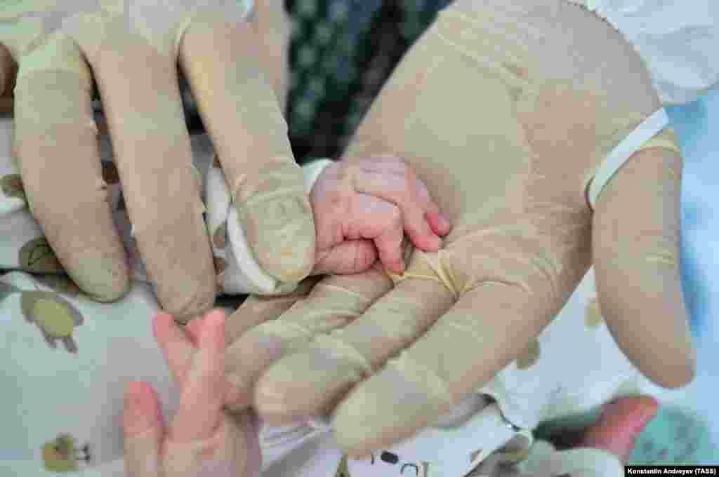 A medic holds a baby&#39;s hand at a children&#39;s hospital treating suspected COVID-19 patients in the Russian Far Eastern city of Khabarovsk on February 10.&nbsp;