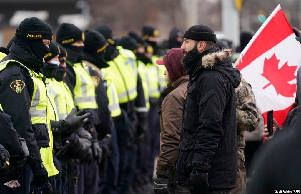 Një protestues përballet me policinë kanadeze në Uindsor të Ontarios. (AFP)  