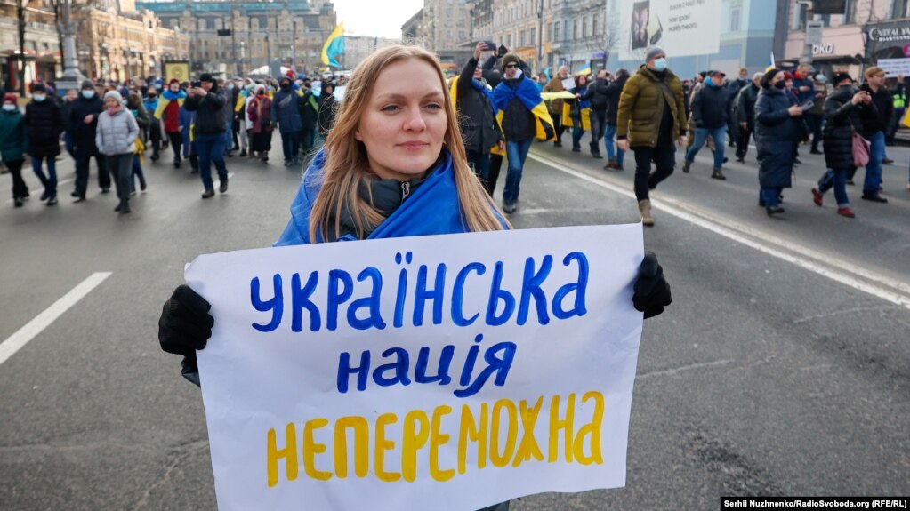 Një grua duke mbajtur një pllakat, me mbishkrimin "Kombi ukrainas është i pamposhtshëm", gjatë Marshit të Unitetit, në Kiev, më 12 shkurt, kundër kërëcnimit të një pushtimi të ri ushtarak të Ukrainës nga Rusia.
