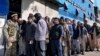 A Taliban fighter stands guard as people wait to enter a bank in Kabul on February 13.