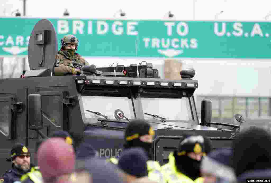 Policia kanadeze në përpjekje për të shpërndarë protestuesit, që bllokuan hyrjen në një urë në Ontario të Kanadasë. Protestat në këtë vend kanë hyrë në javën e tretë dhe kanë frymëzuar veprime të ngjashme në disa vende të botës. (AFP)