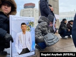 Собравшиеся держат фотографии убитых, раненых и задержанных во время Январских событий.