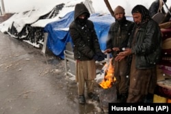 Afghan men warm themselves around a bonfire during snowy weather at a popular market in Kabul.